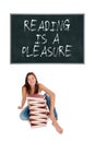 Laughing schoolgirl with a huge pile of books in front of a blackboard Royalty Free Stock Photo
