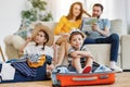 Playful kids in suitcases with parents on sofa behind Royalty Free Stock Photo