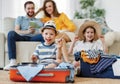 Playful kids in suitcases with parents on sofa behind Royalty Free Stock Photo