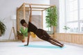 Laughing, smiling multicultural woman do yoga exercises on mat. Practicing Vasisthasana side plank with one arm indoors