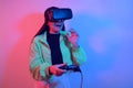 Laughing smiling surprise girl in neon with VR glasses holds a gamepad in her hands and plays games. Virtual world, technology Royalty Free Stock Photo