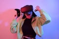 Laughing smiling surprise girl in neon with VR glasses holds a gamepad in her hands and plays games. Virtual world, technology Royalty Free Stock Photo