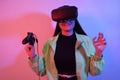 Laughing smiling surprise girl in neon with VR glasses holds a gamepad in her hands and plays games. Virtual world, technology Royalty Free Stock Photo