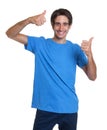 Laughing spanish guy in a blue shirt showing both thumbs up