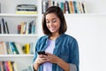 Laughing spanish young adult woman sending message with mobile phone