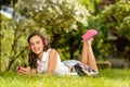 Laughing student girl with headphones lying grass