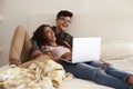 Laughing teenage couple hanging out in bedroom using laptop Royalty Free Stock Photo