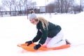 A laughing teenage girl on an orange sled