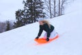 A laughing teenage girl,sliding down a winte hill