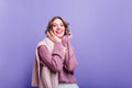 Laughing trendy girl in winter headphones posing in studio. Indoor photo of inspired happy woman in stylish accessories