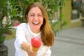 Laughing vivacious woman offering an ice cream cone to camera