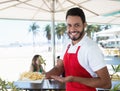 Laughing waiter serving french fries at beach bar