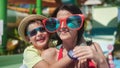 Laughing woman in big funny glasses hugging little son enjoying vacation having fun together