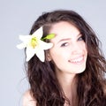 Laughing woman with flower in curly hair with smile with teeth. SPA treatment. Royalty Free Stock Photo