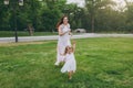 Laughing woman in light dress running catching up with little cute child baby girl on green grass lawn in park. Mother Royalty Free Stock Photo