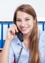 Laughing woman with long blond hair at office talking at phone Royalty Free Stock Photo