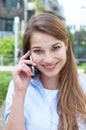 Laughing woman with long blond hair speaking at phone outside Royalty Free Stock Photo