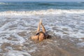 A laughing woman on the sand under a rising wave on the shore of the Indian ocean on the island of Sri Lanka