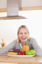 Laughing woman sitting behind plate of fruits Royalty Free Stock Photo