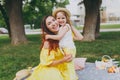 Laughing woman in yellow clothes play in park have fun and hug, embrace with little child baby girl hold soap bubble Royalty Free Stock Photo