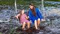 A woman and a young girl are swinging across a fast-flowing river, laughing and splashing with water Royalty Free Stock Photo