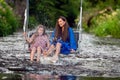 a woman and a young girl are swinging across a fast-flowing river, laughing and splashing with water Royalty Free Stock Photo