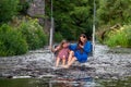a woman and a young girl are swinging across a fast-flowing river, laughing and splashing with water Royalty Free Stock Photo