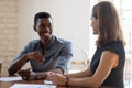 Laughing young african american male employee joking with female colleague.