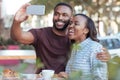 Laughing young African couple taking selfies at a sidewalk cafe Royalty Free Stock Photo