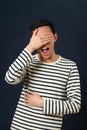 Laughing young Asian man covering his face by palm Royalty Free Stock Photo