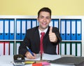 Laughing young businessman at office showing thumb Royalty Free Stock Photo