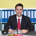 Laughing young businessman writing a note at office Royalty Free Stock Photo