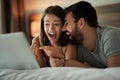 Laughing couple in bedroom using laptop Royalty Free Stock Photo