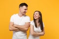 Laughing young couple two friends guy girls in white blank empty design t-shirts posing isolated on yellow orange wall Royalty Free Stock Photo