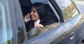 Laughing young executive on phone in car