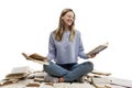 A laughing young girl in jeans and a blue T-shirt sits on a pile of opened books and holds books in her hands. Education and Royalty Free Stock Photo