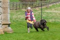Laughing young girl running with black labradoodle dog in a rural setting