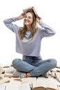 A laughing young girl sits on a pile of opened books and holds a book on her head. Education and knowledge. Isolated on a white Royalty Free Stock Photo