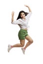 Laughing young girl in a white shirt and green shorts is jumping. Brunette with long hair. Isolated on a white background. Royalty Free Stock Photo