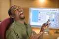 Laughing young man with cell phone and computer