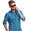 Laughing young man wearing sunglasses talks on the phone Royalty Free Stock Photo