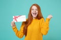 Laughing young redhead woman girl in yellow knitted sweater posing isolated on blue turquoise wall background. People Royalty Free Stock Photo