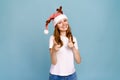Laughing young santa girl in funny decorative deer horns on her head, pointing