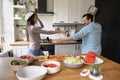 Laughing young spouses cooking food joking fighting on kitchen tools