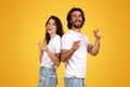 Laughing young woman and bearded man standing back to back, playfully pointing fingers at the camera Royalty Free Stock Photo