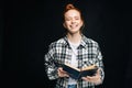 Laughing young woman with closed eyes college student holding opened book on black isolated background. Royalty Free Stock Photo