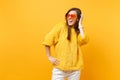 Laughing young woman with closed eyes in fur sweater and heart orange glasses putting hand on head isolated on bright Royalty Free Stock Photo