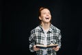 Laughing young woman college student with closed eyes holding opened book on black background. Royalty Free Stock Photo