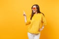 Laughing young woman in fur sweater, heart orange glasses pointing index finger aside on copy space isolated on bright