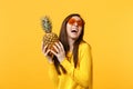 Laughing young woman in heart glasses holding in hands fresh ripe pineapple fruit isolated on yellow orange background Royalty Free Stock Photo